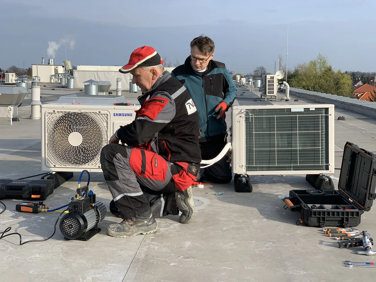Prace instalacyjne przy urządzeniach klimatyzacyjnych na dachu.